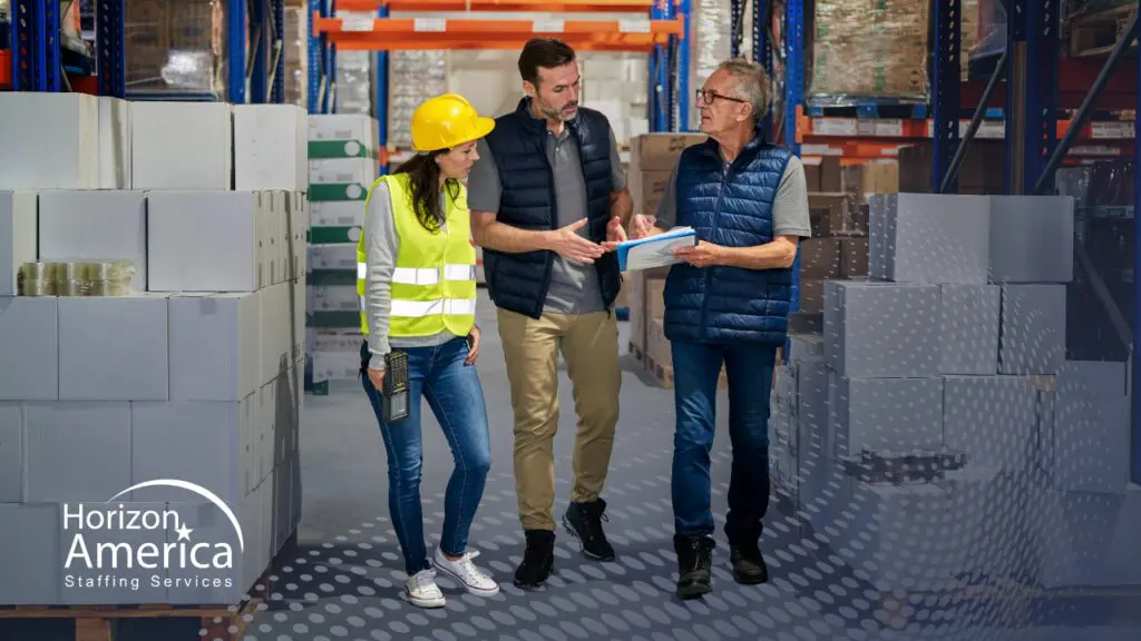 Warehouse workers in safety gear discuss work