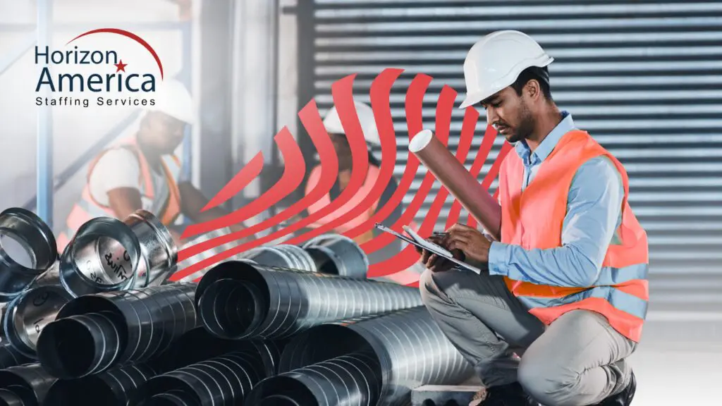 Light industrial professional in a hard hat and safety vest takes notes in his workplace