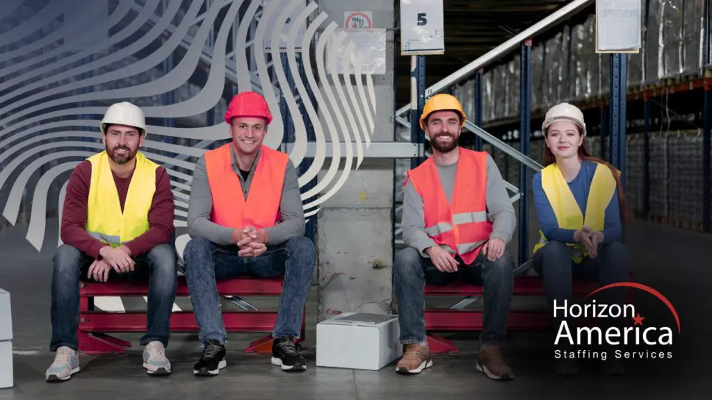 Warehouse and logistics professionals sit in a row wearing safety gear