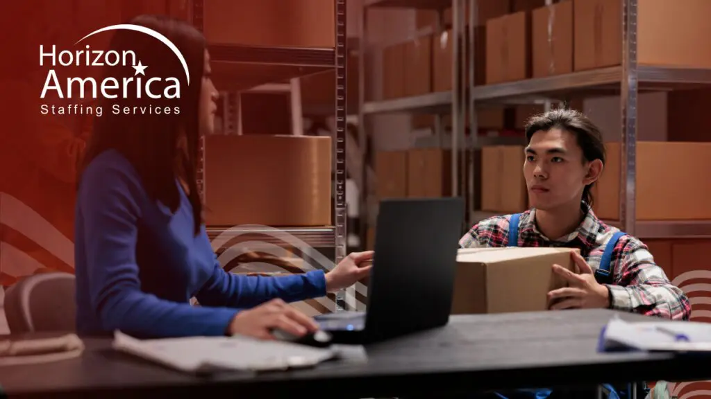 Warehouse professional holds a box while speaking to an interviewer with laptop