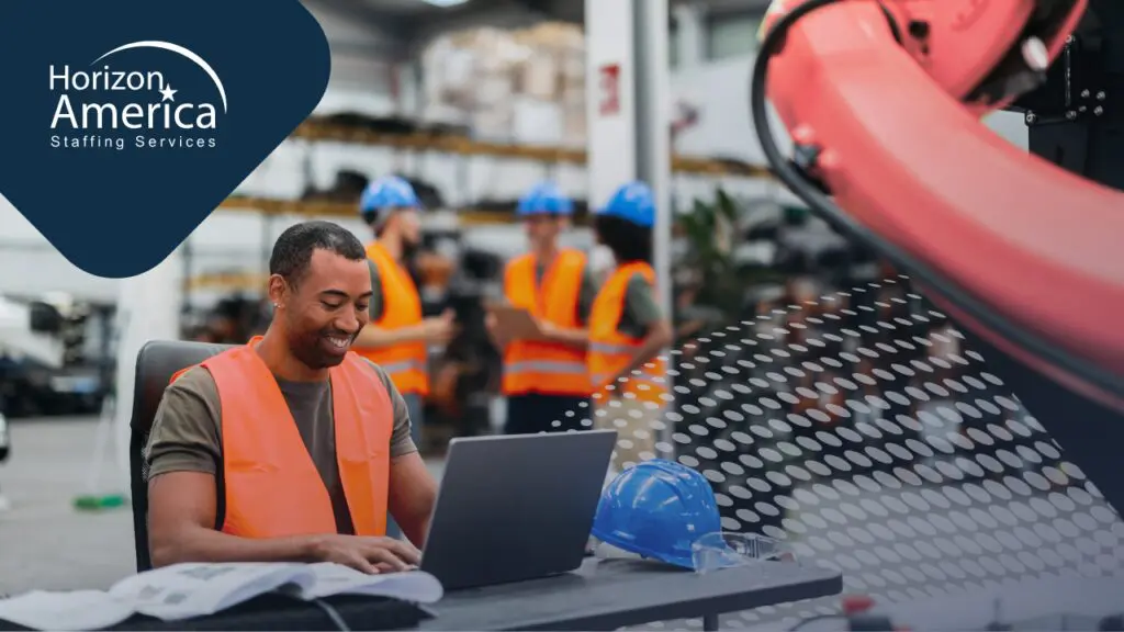 Light industrial worker uses a laptop in his workplace with a smile, symbolizing meaningful workplaces