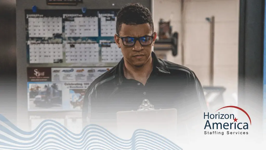 A light industrial employee looks at a clipboard.