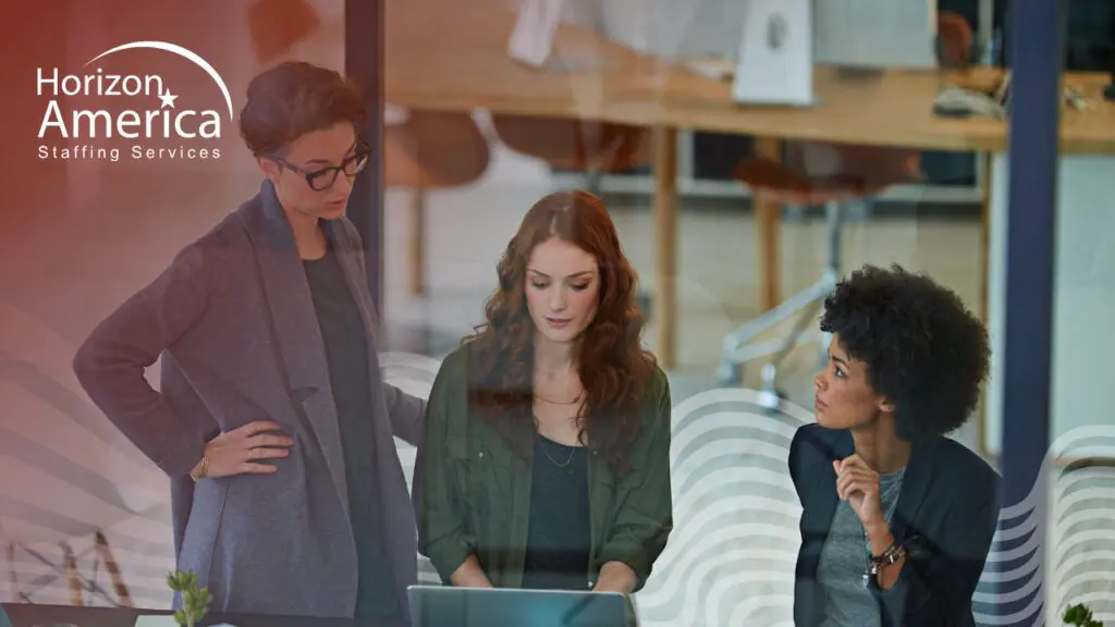 Three professionals reviewing data on a laptop in an office setting