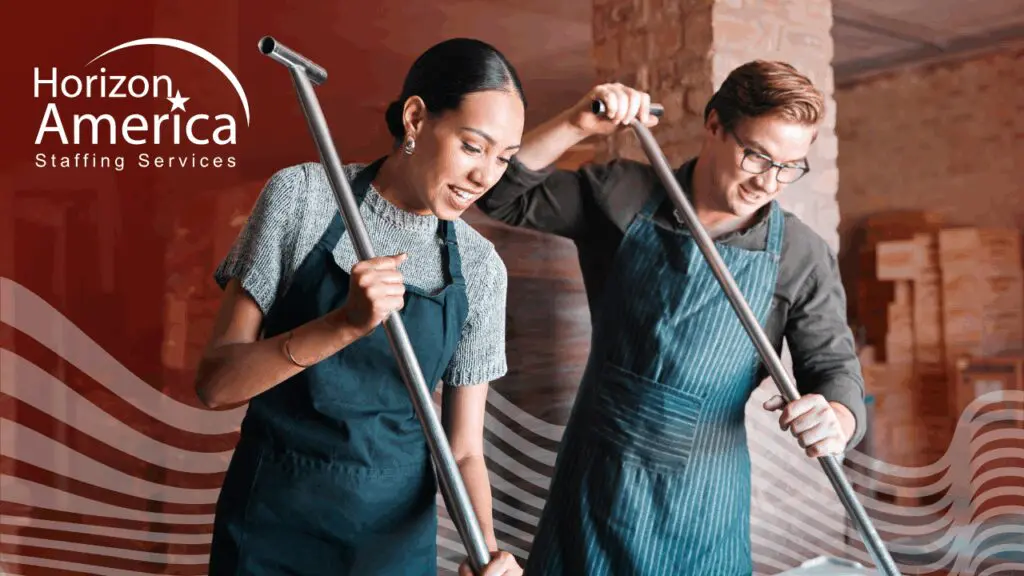 Two light industrial workers work side by side in aprons