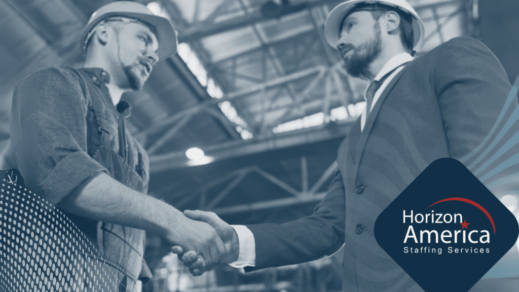 An industrial worker in hard hat shakes hands with a manager in a suit and hard hat