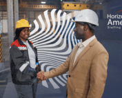 Manufacturing manager and employee in hard hats shake hands