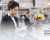 HR staff in corporate attire stands writing in a notebook in an industrial plant